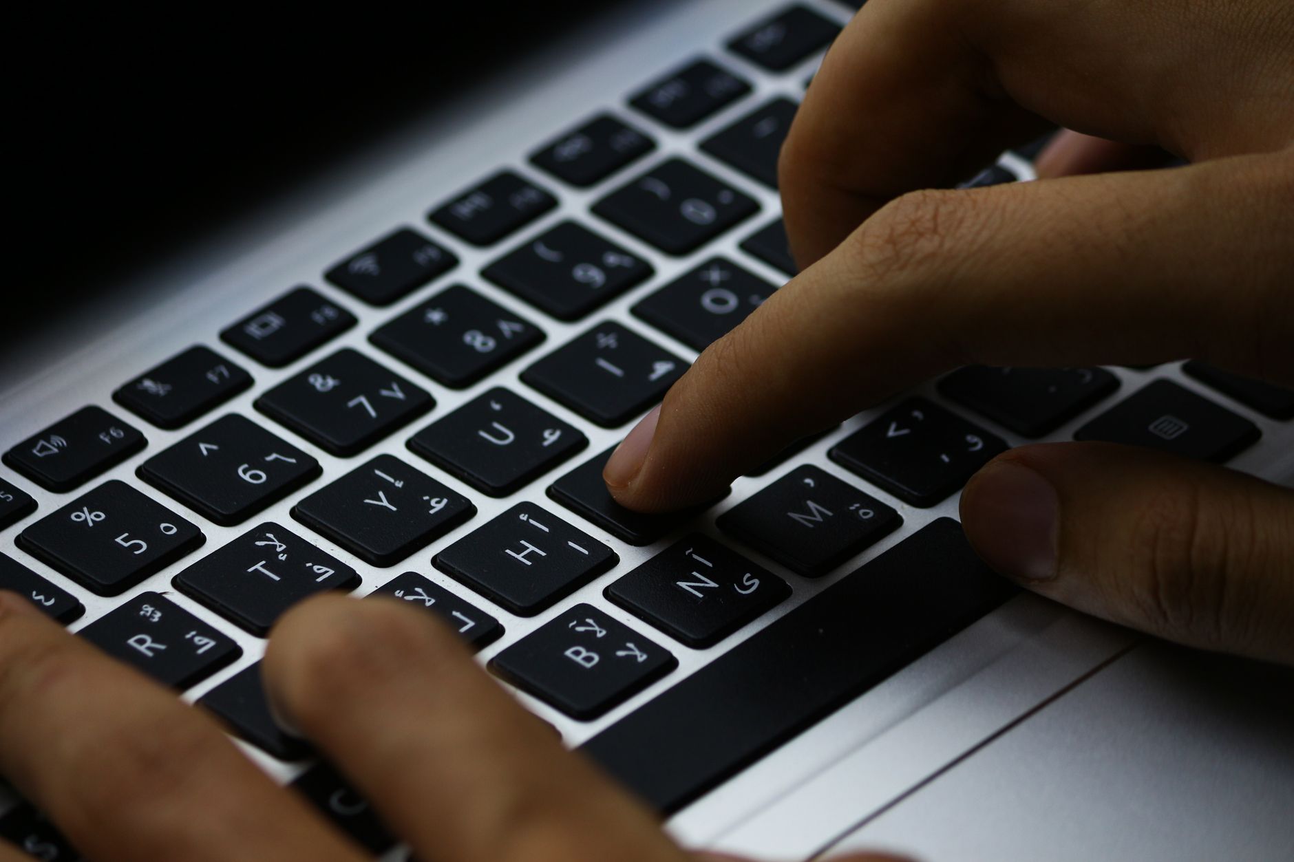 Close-up of hands typing on a laptop keyboard, working through a checklist.