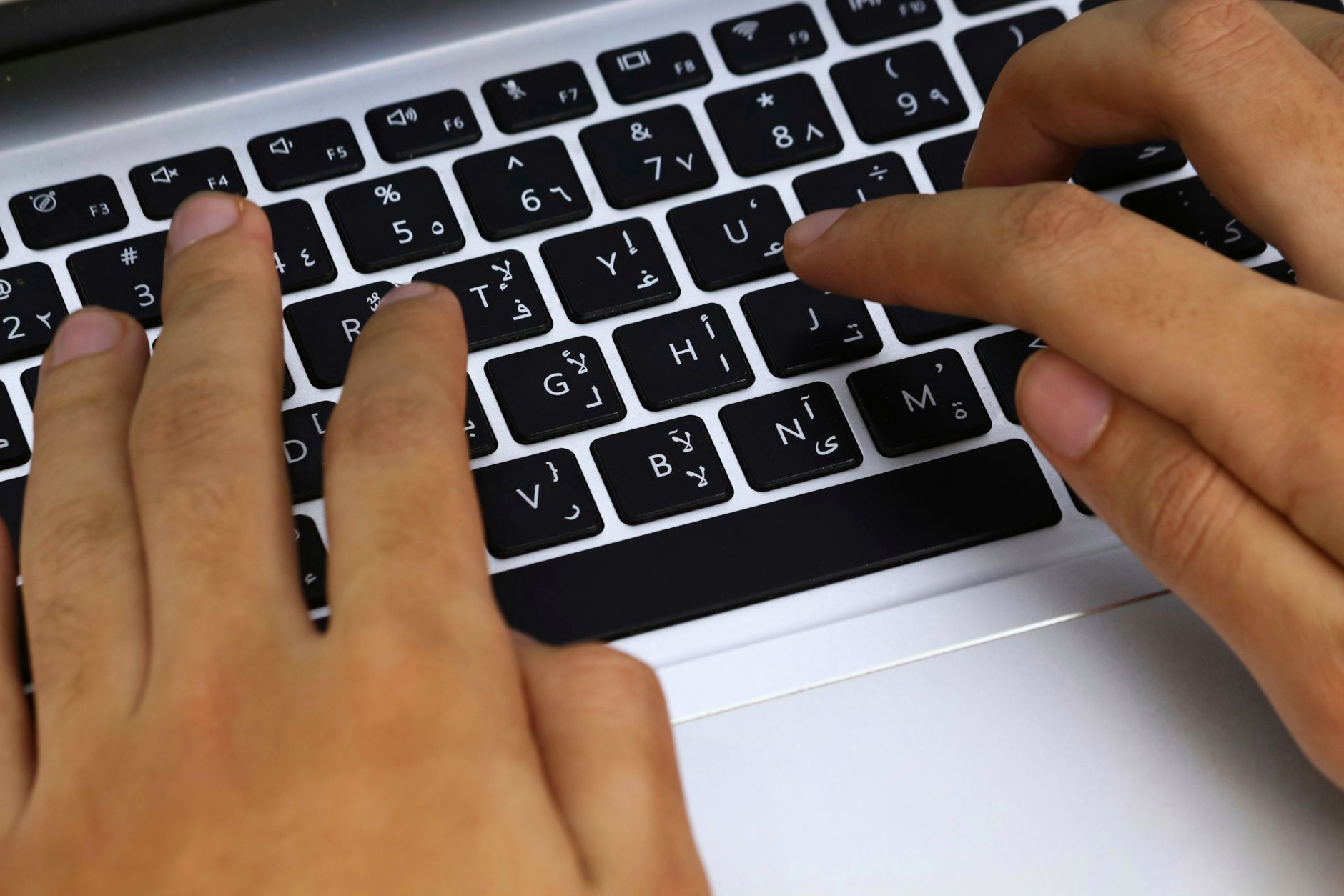 Close-up of hands typing on a laptop keyboard at the end of the day.