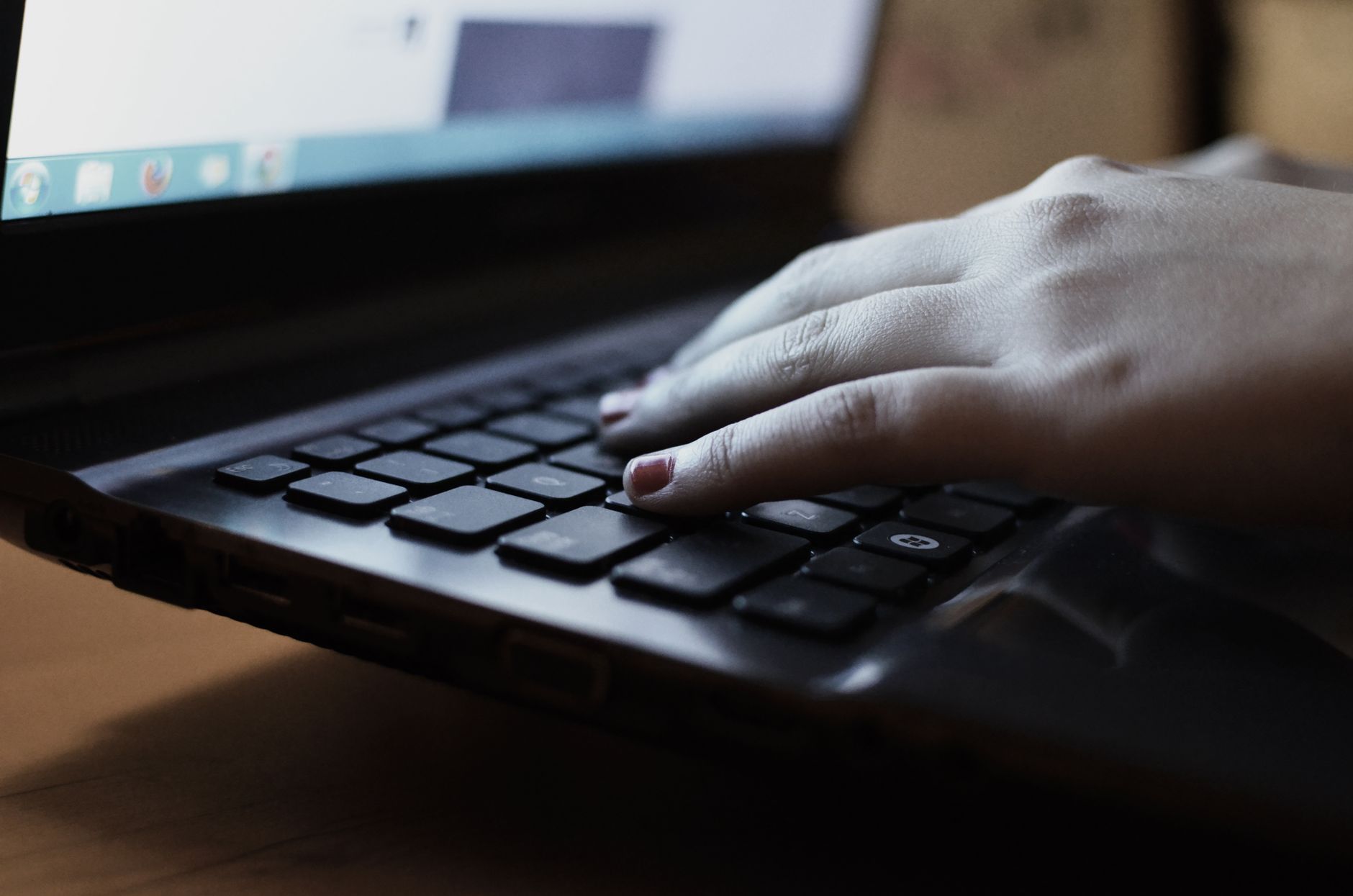 A person typing on a laptop keyboard, reviewing client work.